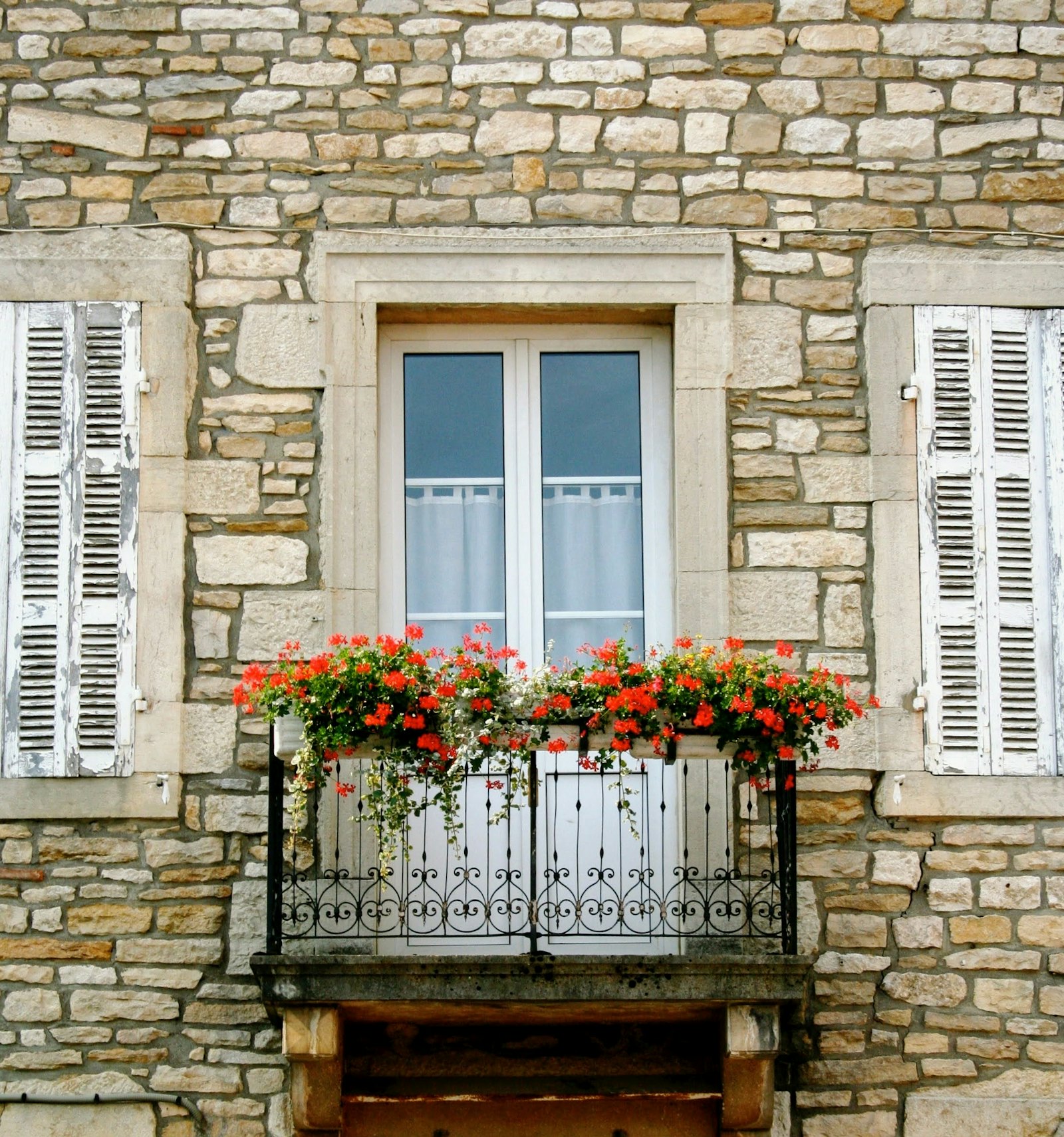 Façade en pierre restaurée, enduit à la chaux et volets bois